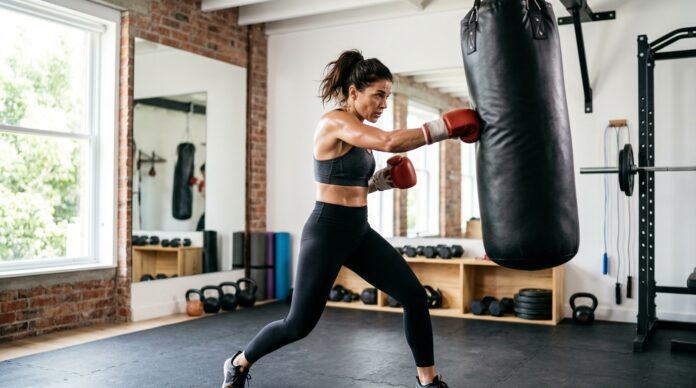 Woman performing a 40 minute boxing workout at home with a heavy bag in a home gym setting